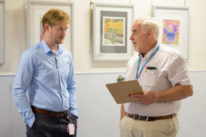 Two men stood chatting over a clipboard