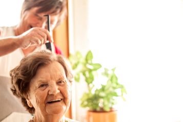 Older lady having her hair done by a carer