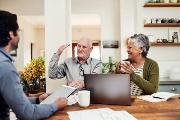 Man at a table with an older couple on a laptop