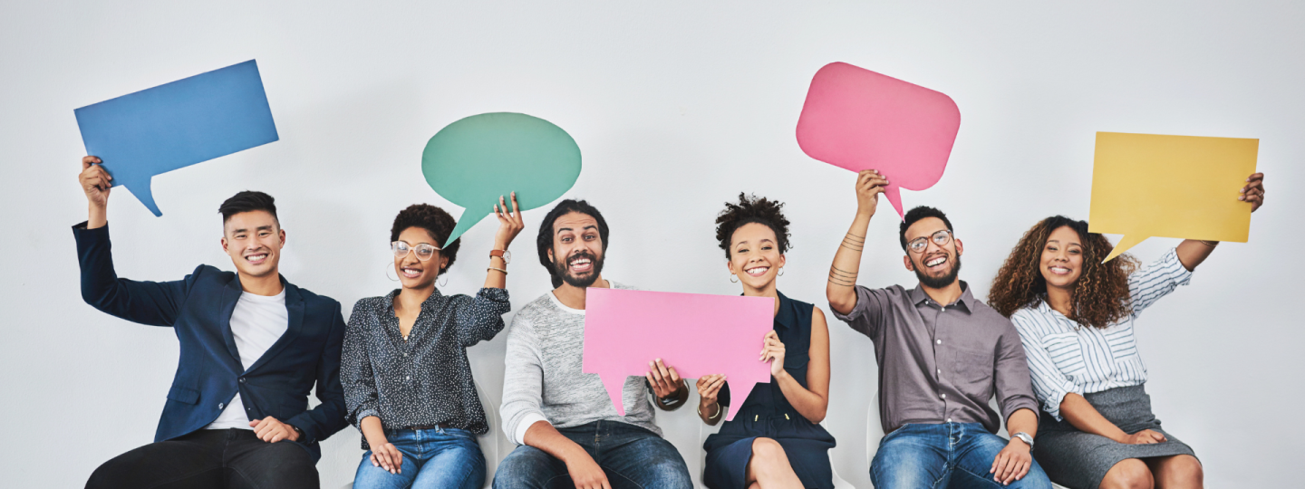 People sitting on chairs in a row holding up speech bubbles