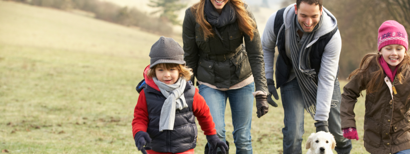 Mum, Dad and two children walking their dog on a cold day